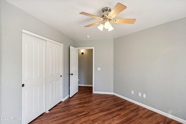 unfurnished bedroom with ceiling fan, dark wood-type flooring, and a closet