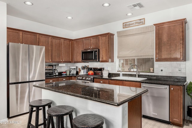 2048 S Martingale Rd, Gilbert, AZ 85295 - kitchen with appliances with stainless steel finishes, a sink, dark stone countertops, a kitchen bar, and recessed lighting