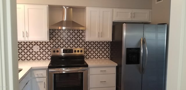 kitchen featuring white cabinets, stainless steel appliances, wall chimney range hood, and decorative backsplash