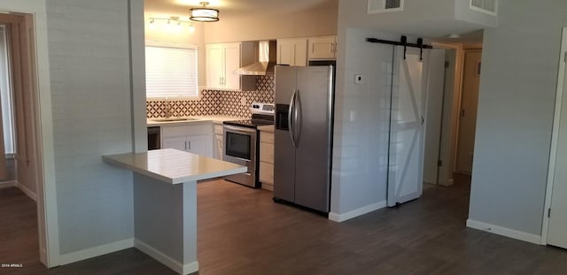 kitchen featuring stainless steel appliances, white cabinetry, wall chimney range hood, and a barn door