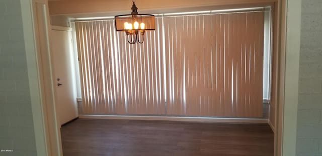 unfurnished room featuring a chandelier and dark hardwood / wood-style flooring