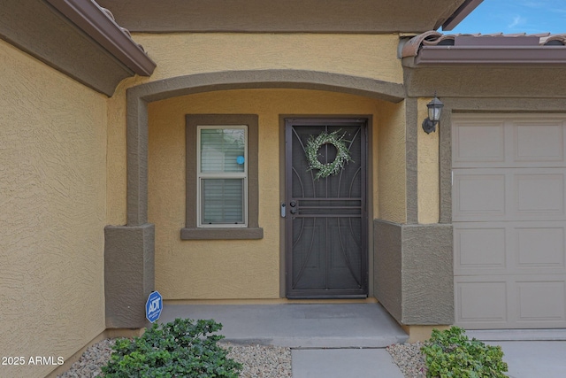 property entrance featuring an attached garage and stucco siding