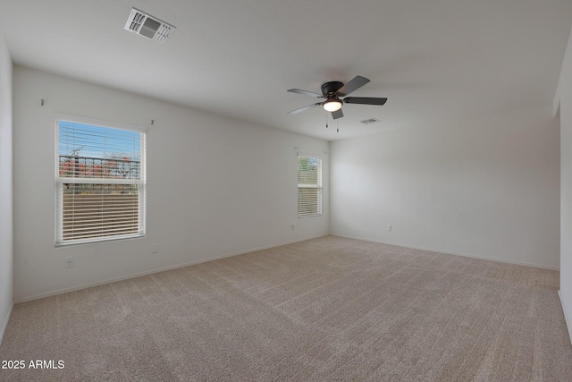 spare room featuring baseboards, a ceiling fan, visible vents, and light colored carpet