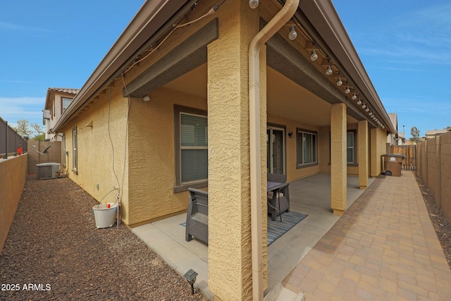 view of side of home with cooling unit, a fenced backyard, a patio, and stucco siding