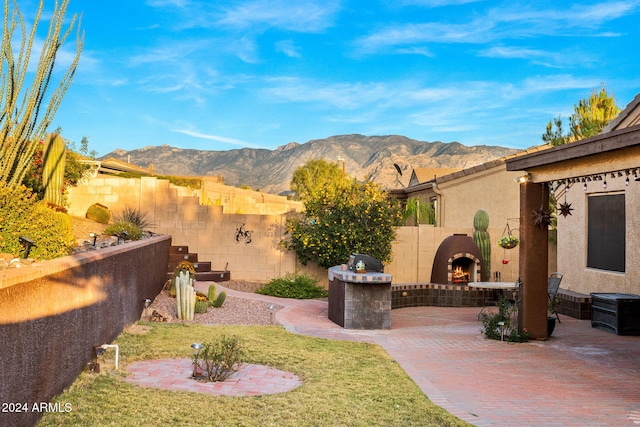 view of yard featuring a mountain view, a patio area, and exterior fireplace