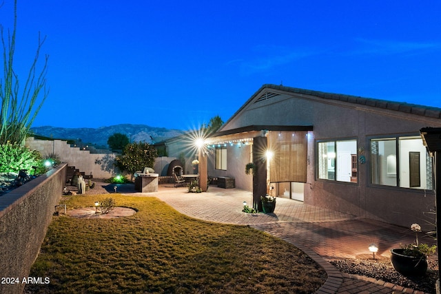 rear view of house with a patio area, a mountain view, and a fireplace