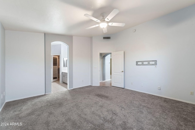 unfurnished bedroom with ceiling fan, light carpet, and ensuite bath