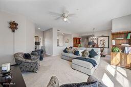 living area with light carpet and ceiling fan with notable chandelier