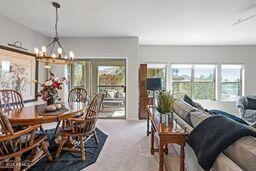 dining area featuring a wealth of natural light, a notable chandelier, and carpet flooring