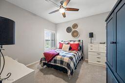 bedroom featuring baseboards, a ceiling fan, and light colored carpet