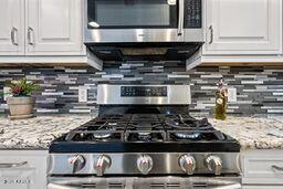 kitchen with tasteful backsplash, appliances with stainless steel finishes, and white cabinets