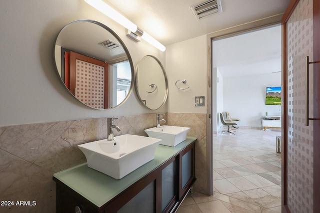 bathroom with a sink, wainscoting, visible vents, and tile walls