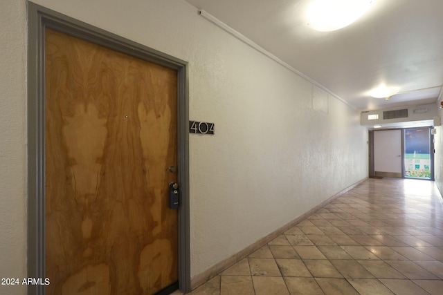 hall with a textured wall, baseboards, and ornamental molding