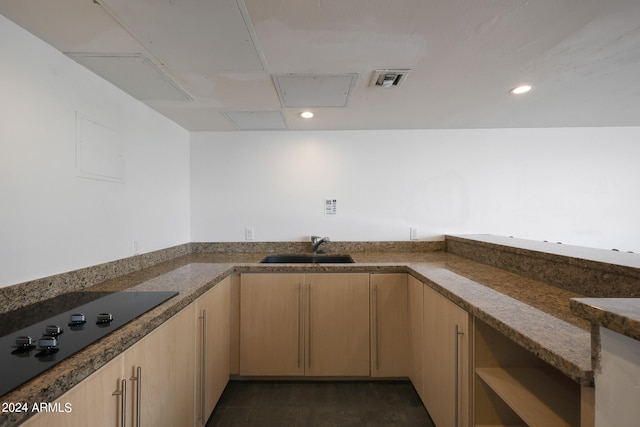 kitchen featuring black electric cooktop, dark stone countertops, sink, and light brown cabinets