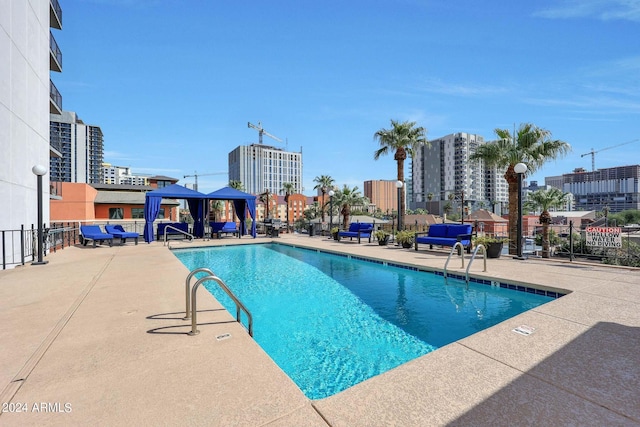 community pool with a patio, a gazebo, a view of city, and fence
