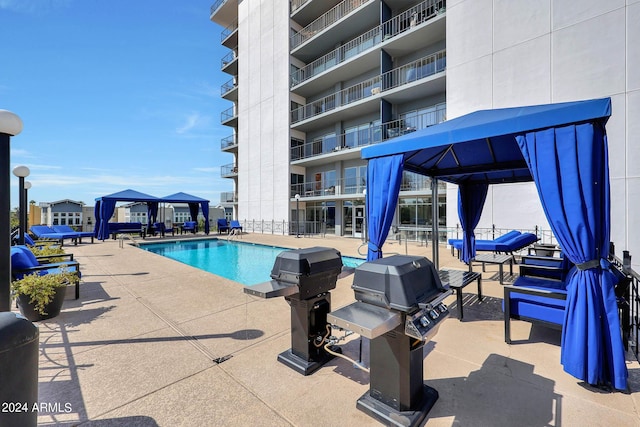 community pool with a gazebo, a patio, and area for grilling