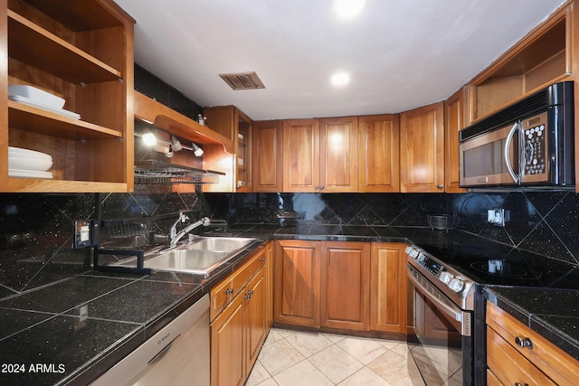 kitchen with open shelves, brown cabinetry, appliances with stainless steel finishes, tile countertops, and a sink