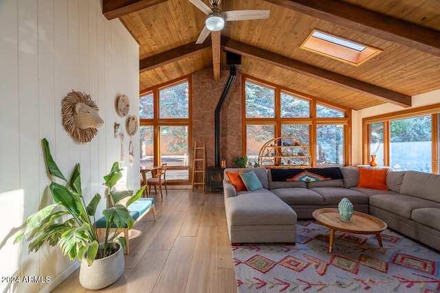 living room with hardwood / wood-style floors, ceiling fan, a wood stove, and a wealth of natural light