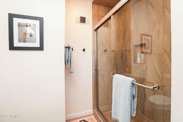 bathroom with toilet and a shower with shower door