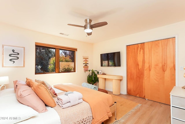 bedroom with ceiling fan, light hardwood / wood-style floors, and a closet