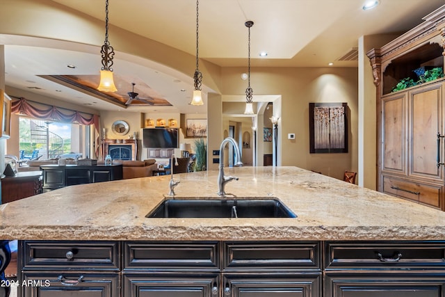 kitchen with sink, an island with sink, and decorative light fixtures