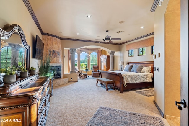 carpeted bedroom with multiple windows, ceiling fan, crown molding, and decorative columns