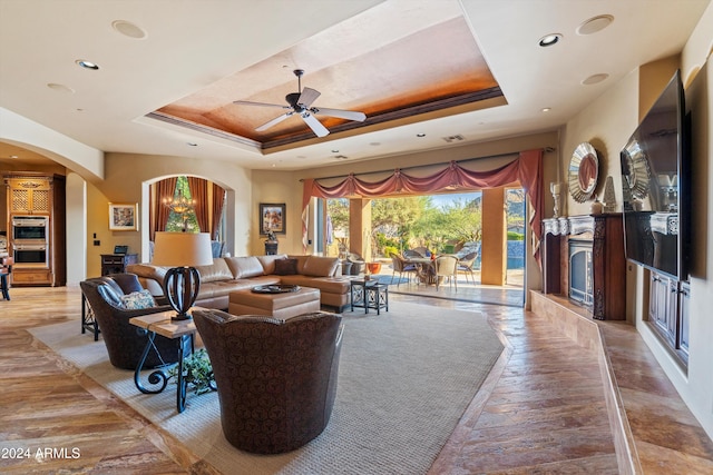 living room with crown molding, ceiling fan, and a raised ceiling