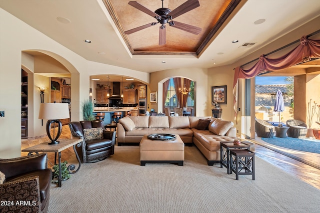 carpeted living room featuring crown molding, a raised ceiling, plenty of natural light, and ceiling fan