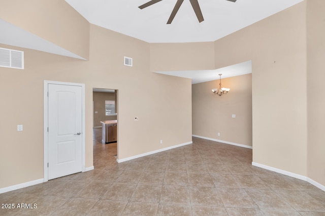 tiled empty room featuring vaulted ceiling and ceiling fan with notable chandelier