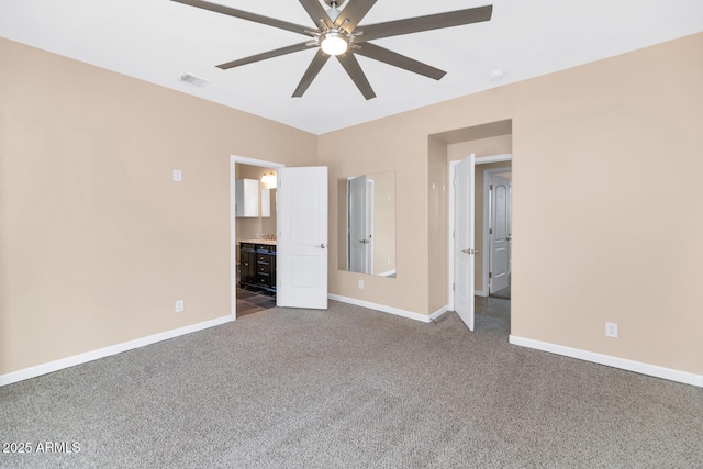 unfurnished bedroom with ceiling fan, ensuite bath, and carpet floors