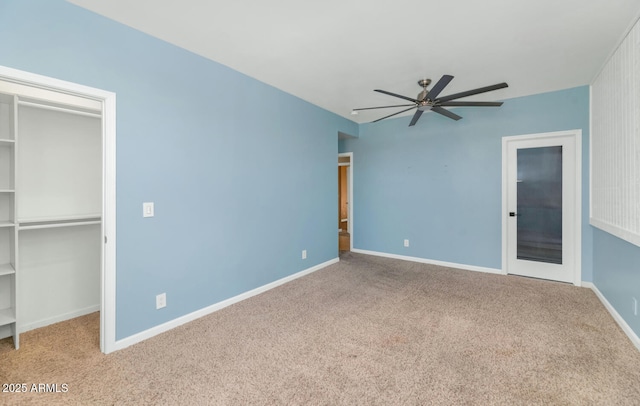 unfurnished bedroom featuring a walk in closet, light colored carpet, a closet, and ceiling fan