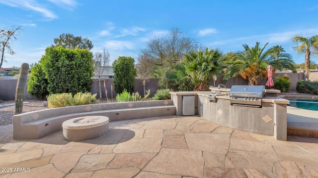 view of patio featuring exterior kitchen, grilling area, and a fire pit