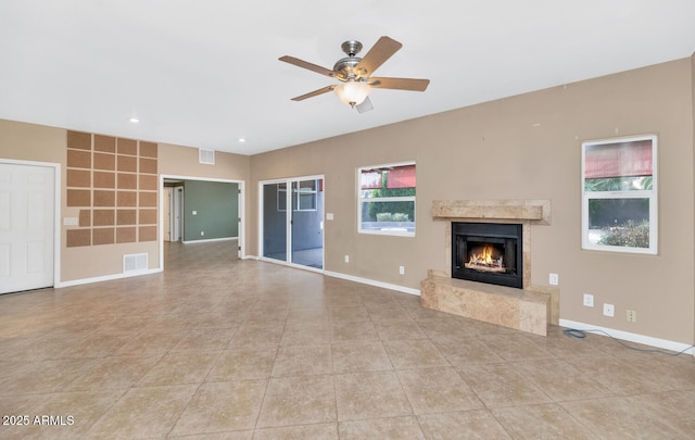 unfurnished living room with a premium fireplace, light tile patterned flooring, and ceiling fan