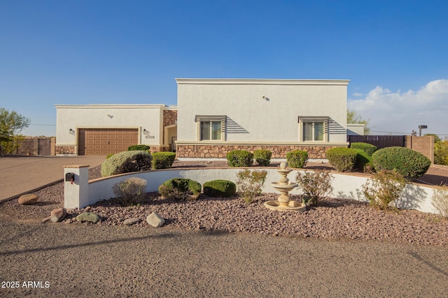 view of front of home with driveway, stone siding, fence, and stucco siding