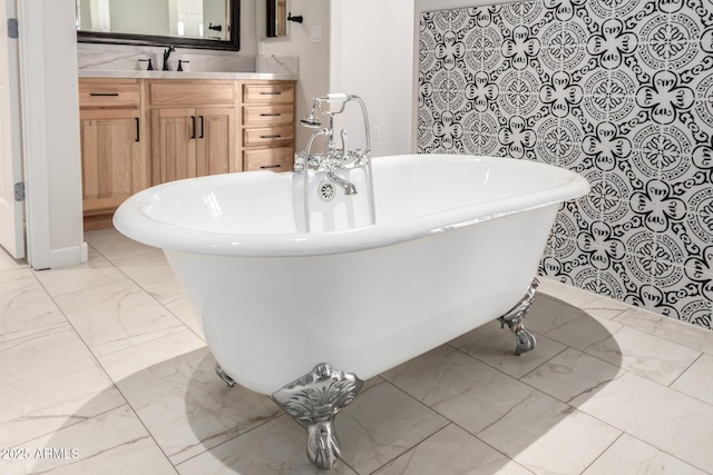 full bathroom featuring marble finish floor, a freestanding tub, and vanity