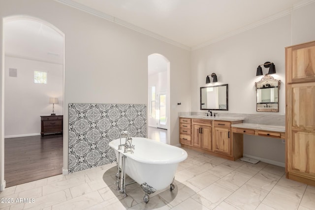 full bathroom featuring marble finish floor, ornamental molding, a freestanding tub, and vanity