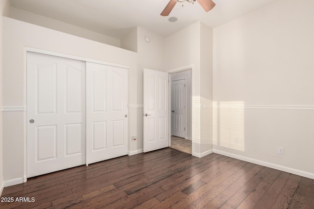 unfurnished bedroom with dark wood-style flooring, a closet, a ceiling fan, and baseboards