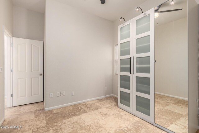 empty room with ceiling fan, baseboards, and stone finish flooring