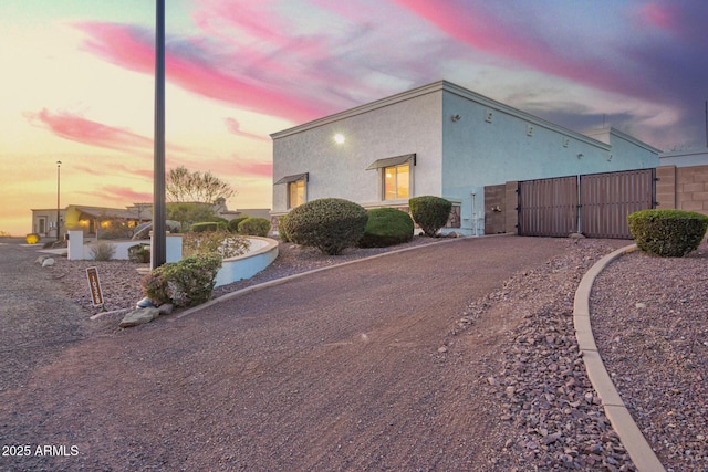 property exterior at dusk with a gate and stucco siding