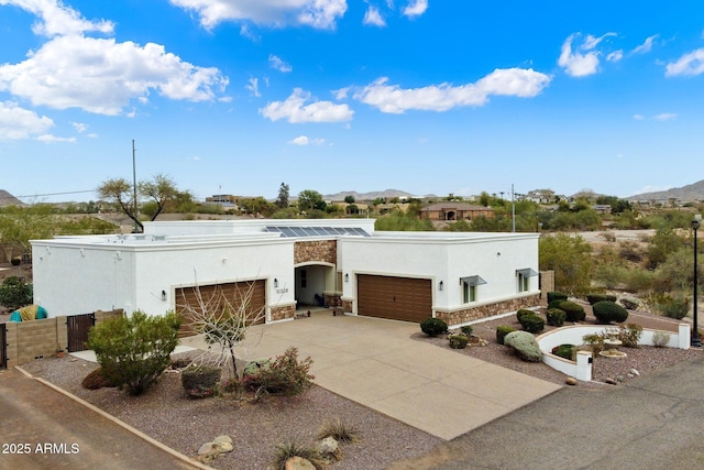 view of front of property with an attached garage, stone siding, concrete driveway, and stucco siding