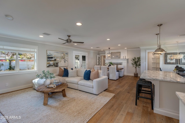 living room with ceiling fan, light wood-type flooring, and ornamental molding