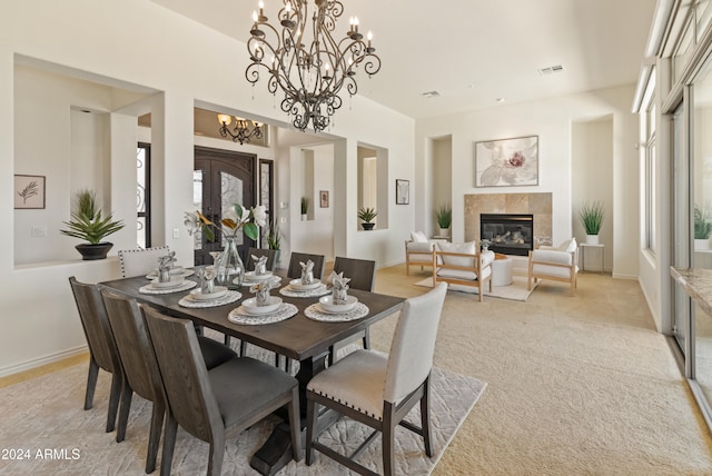 dining area with a notable chandelier, a tiled fireplace, light carpet, and french doors