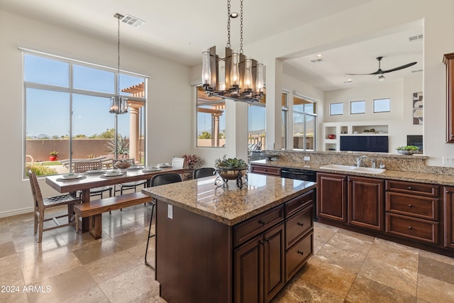 kitchen featuring dark brown cabinets, light stone countertops, sink, and ceiling fan with notable chandelier