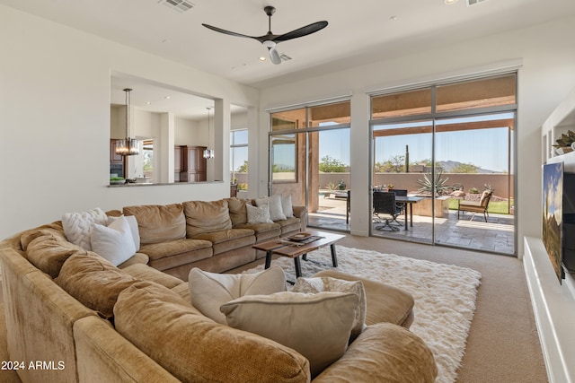 carpeted living room with ceiling fan with notable chandelier