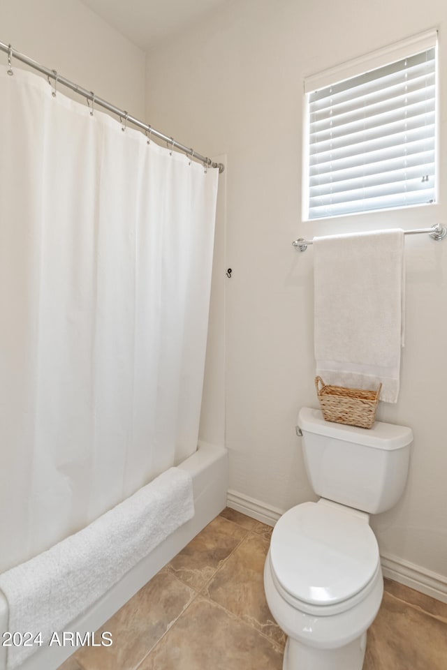 bathroom featuring toilet, shower / tub combo, and tile patterned flooring