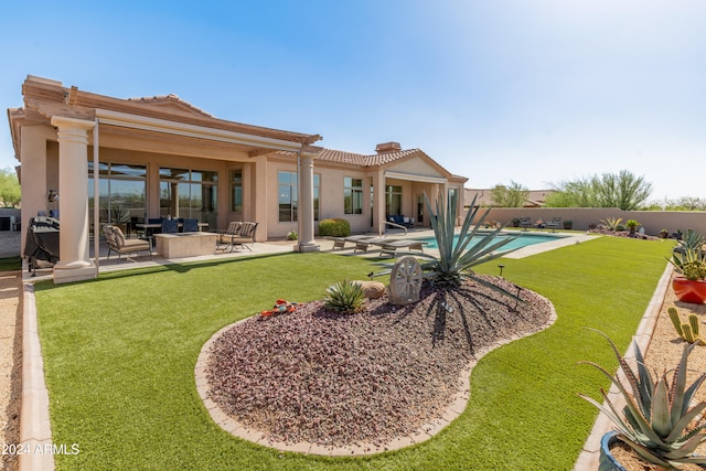 rear view of house with a yard, a patio area, and a fenced in pool