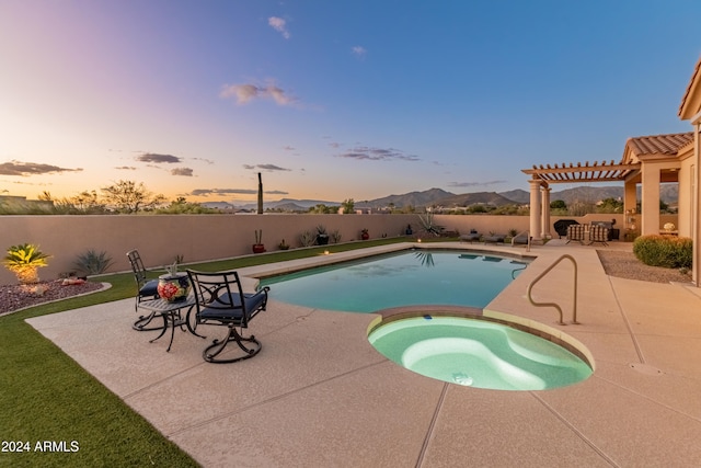 pool at dusk with an in ground hot tub, a mountain view, a pergola, and a patio area