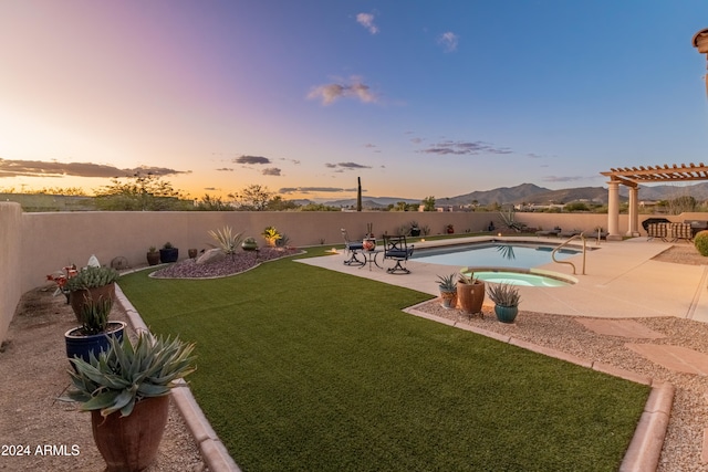 yard at dusk featuring a swimming pool with hot tub, a patio area, a mountain view, and a pergola