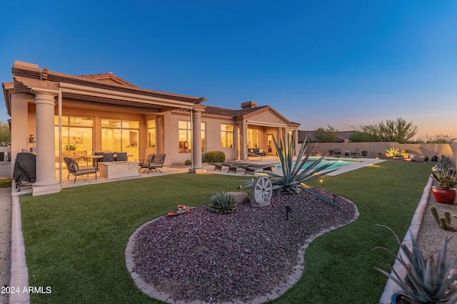 back house at dusk with a fenced in pool, a patio area, and a lawn