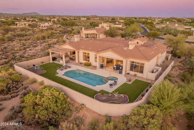 pool at dusk with a yard and a patio area